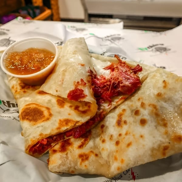 The EVthing's quesadilla with red filling and melted cheese, served with a side of salsa.